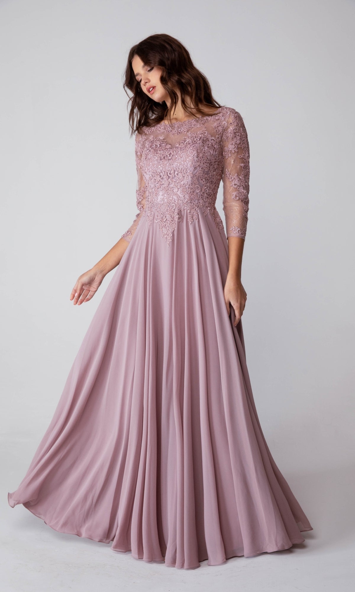 A woman in the Eureka 6909 Long-Sleeve Long Formal Dress, featuring a lace bodice and flowing mauve A-line skirt, stands against a plain light background.